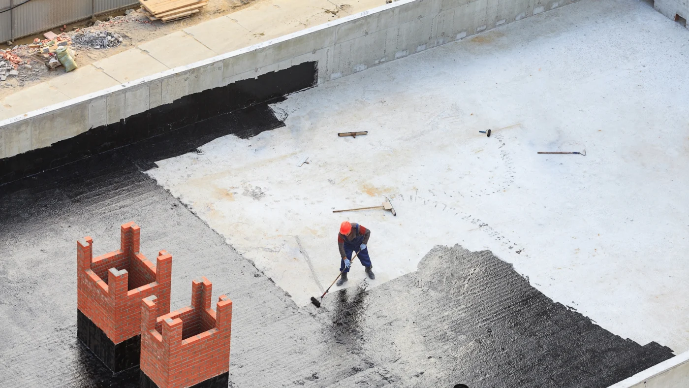 A roofer on a flat roof adding a coating in North Jersey