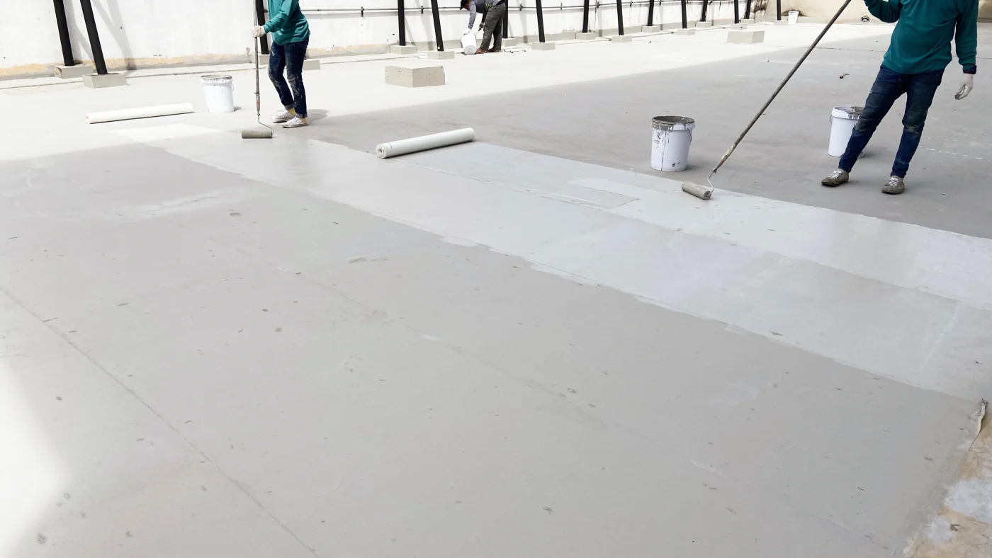 Roofers applying a flat roof coating