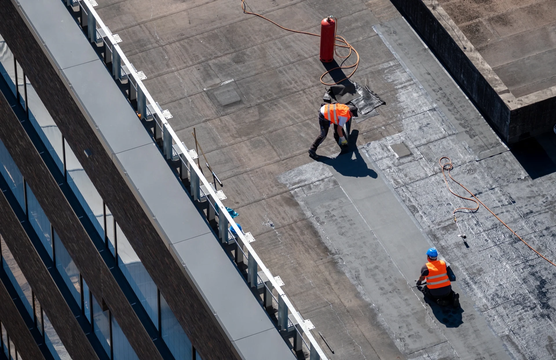 Workers Using Coating On Flat Roof