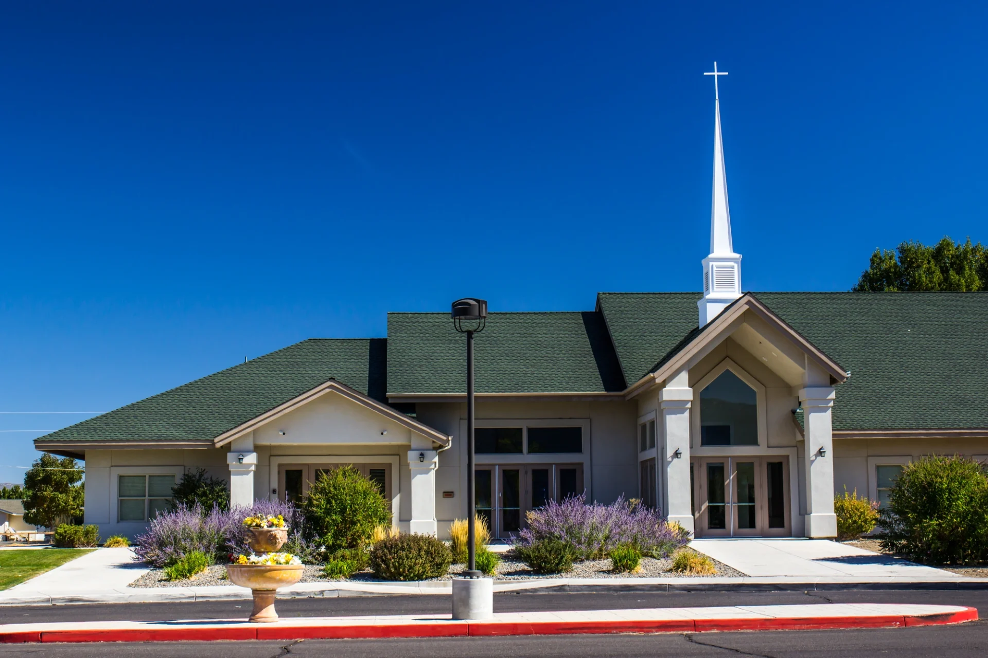 Church with green roof and white steeple with garden