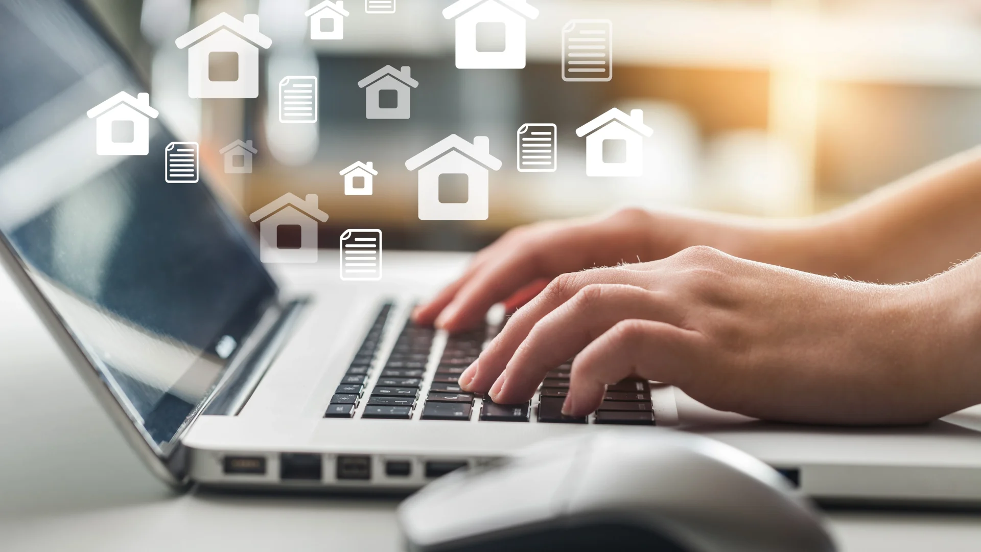 Close view of a real estate broker typing on a laptop with images of houses hovering above it