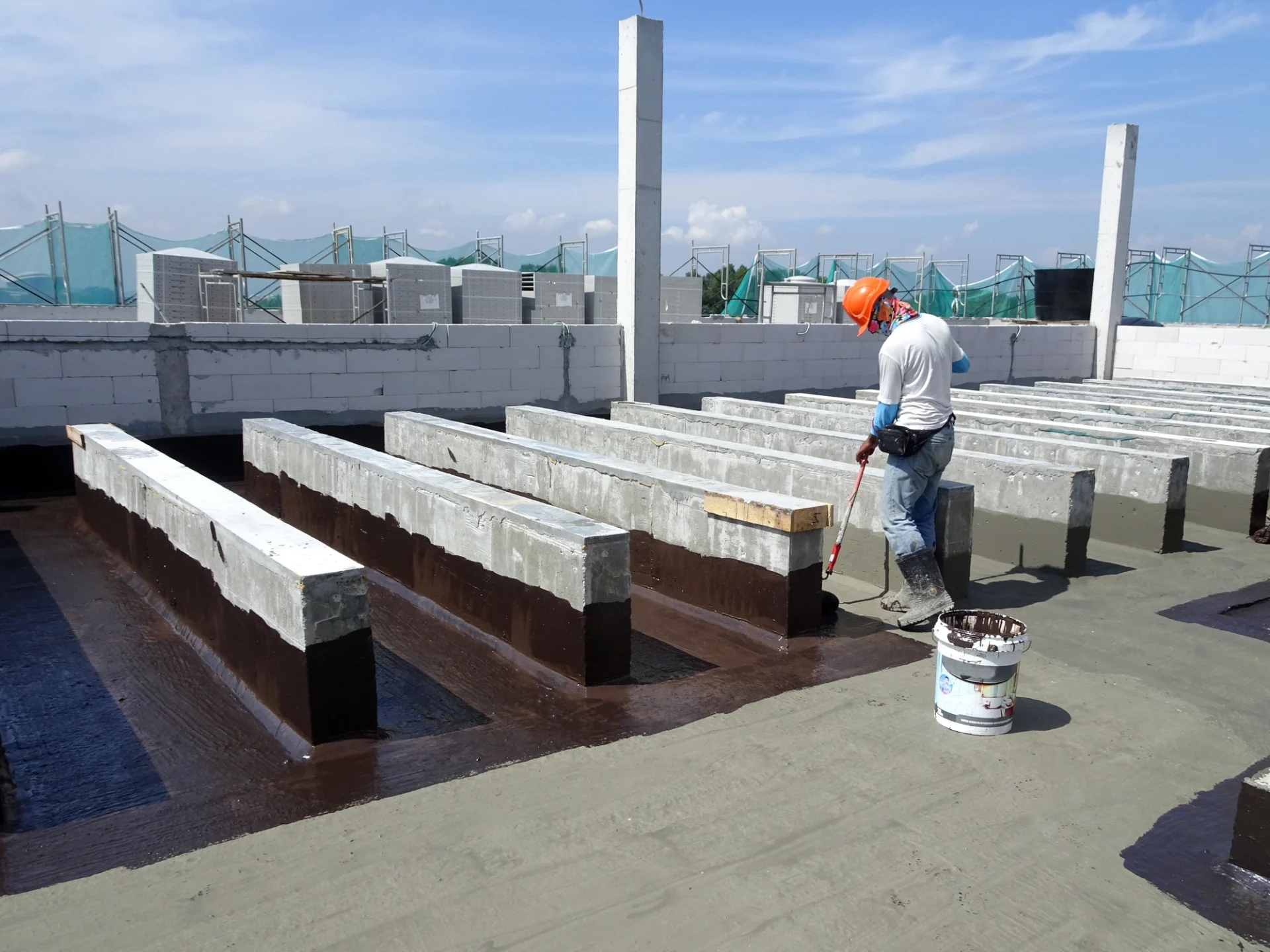Worker Coating Flat Roof Of Industrial Building
