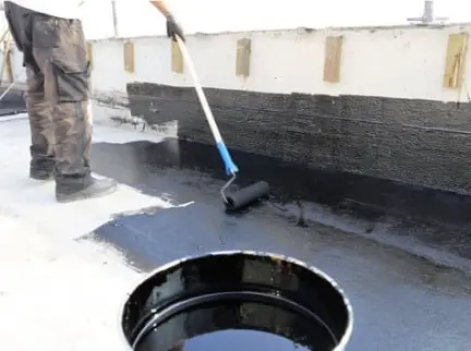 Black Flat Roof Coating Being Applied To Roof