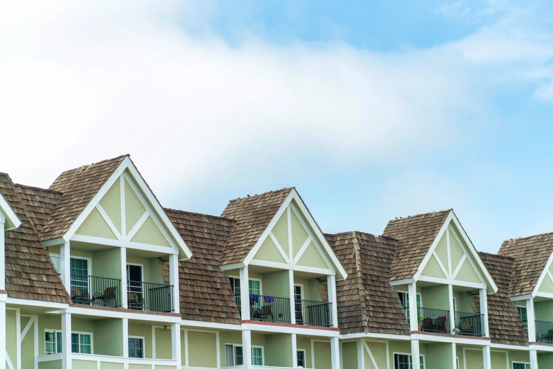 Row of light green apartments with white trim and brown cedar shakes roof