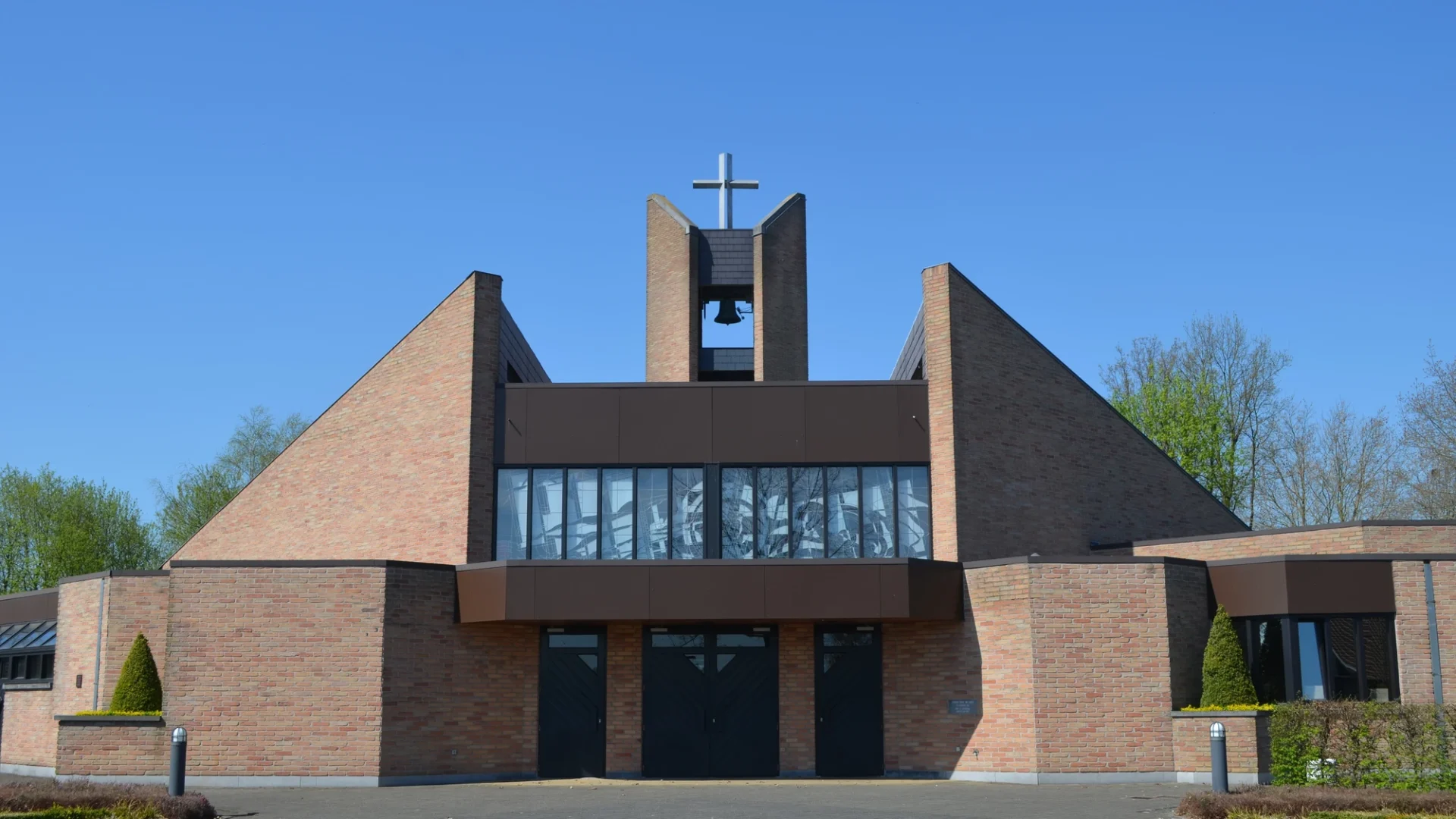 A large brick modern church with a primarily flat roof except for a tall steeple