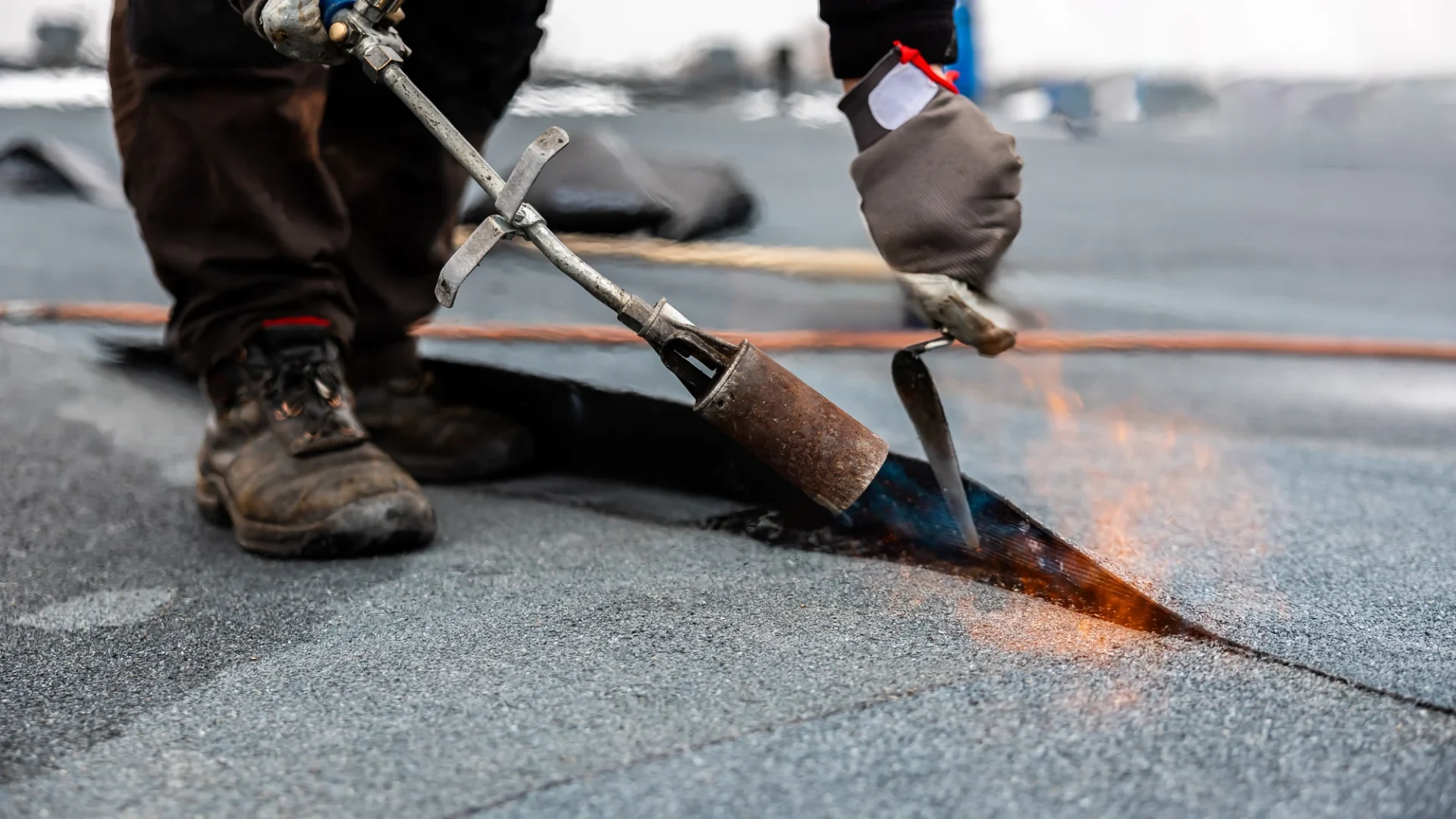 Close view of a roofer closing the seam on a section of commercial roofing