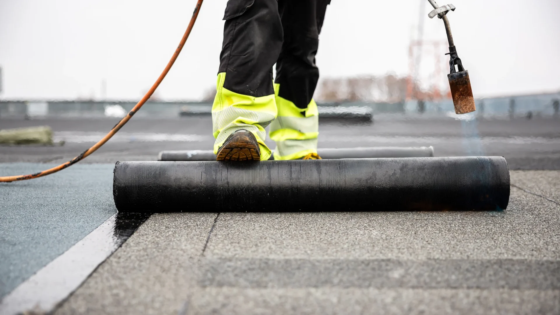 Close view of a roofer waterproofing a commercial roof