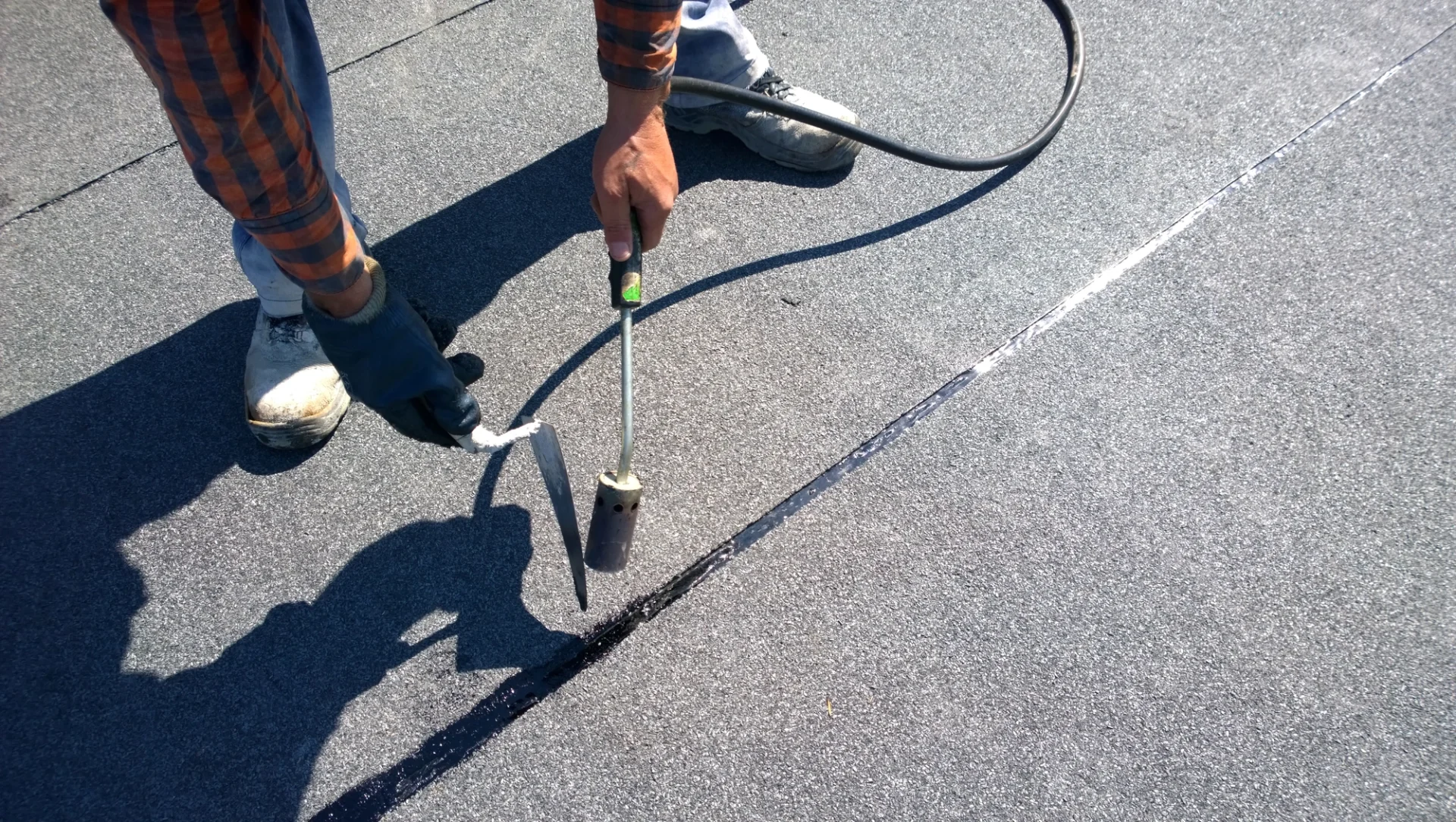 Close view of a roofer closing a seam on a flat commercial roof