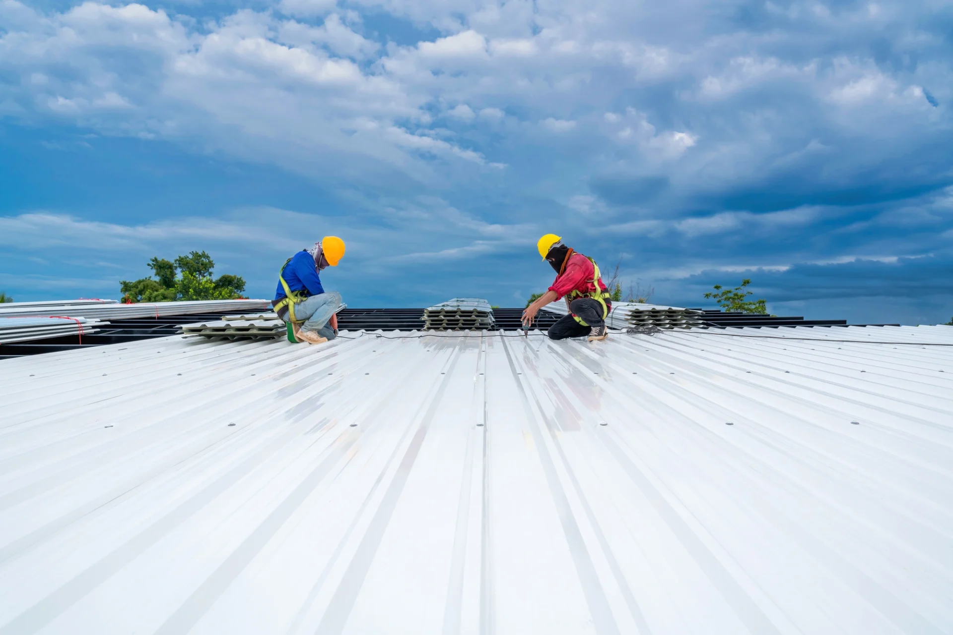 Two people are working on a white roof