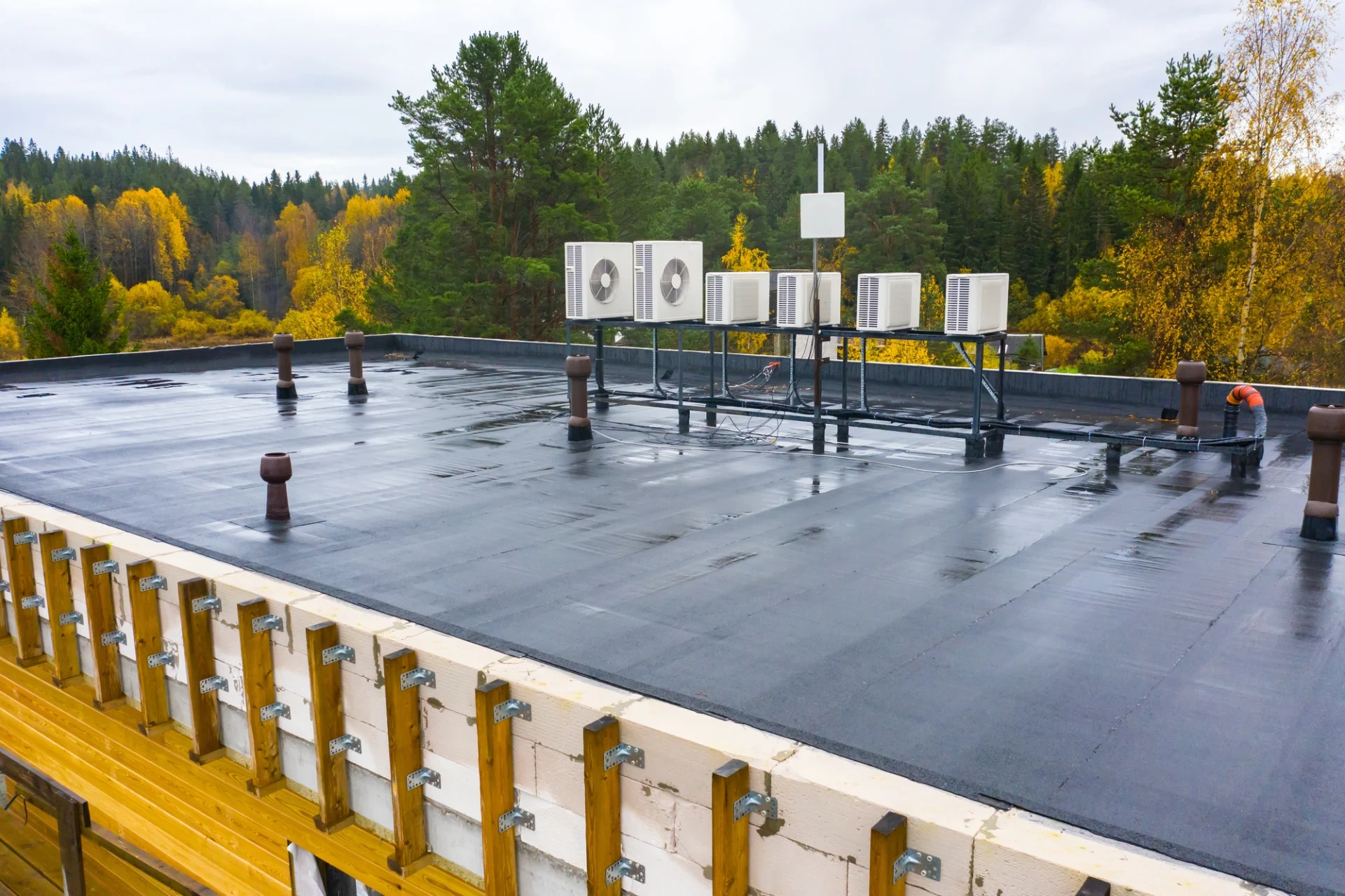 The flat roof of a commercial building with a waterproof coating wet with rain