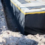 A close-up view of a brand-new commercial building foundation with a waterproofing coating applied