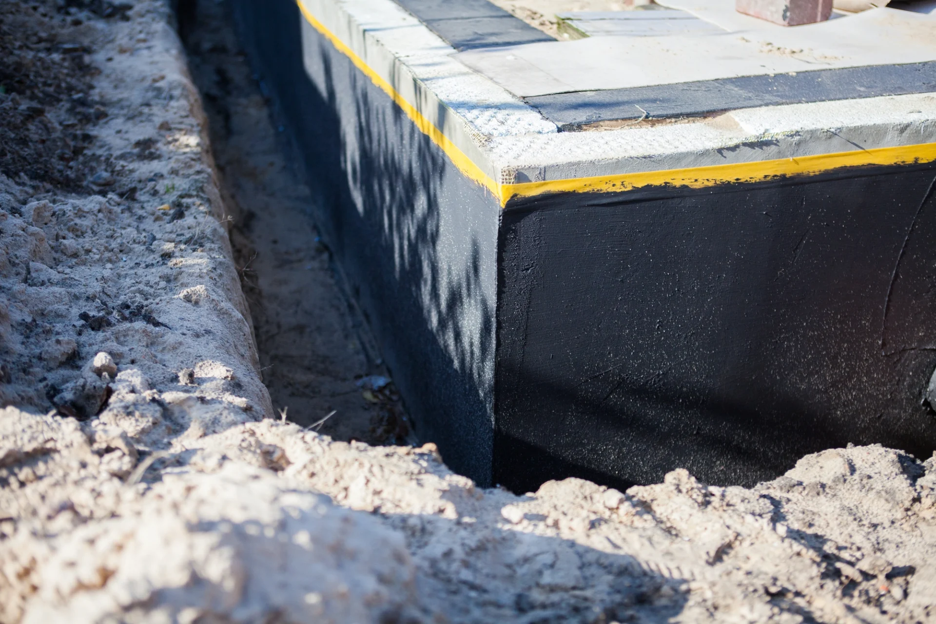 A close-up view of a brand-new commercial building foundation with a waterproofing coating applied